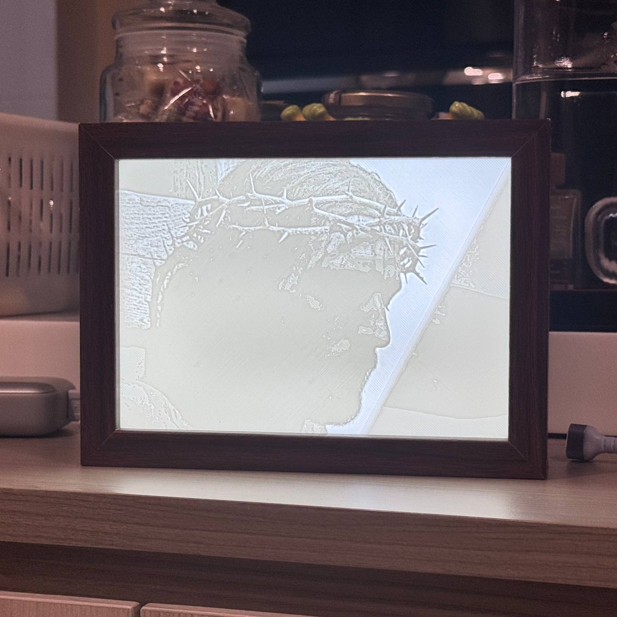 A lithophane light box, lit from behind, showing Christ crowned with thorns